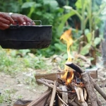 vecteezy_close-up-man-holds-old-black-pot-to-cook-on-bonfire_33368347