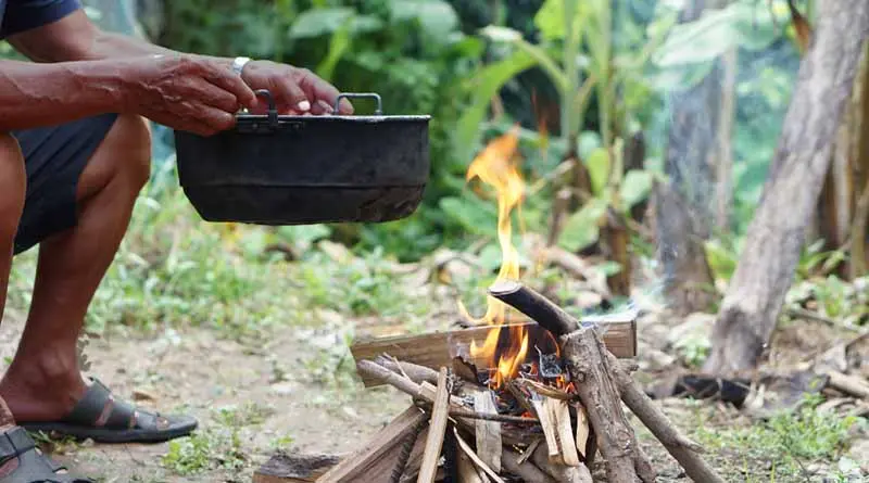 vecteezy_close-up-man-holds-old-black-pot-to-cook-on-bonfire_33368347