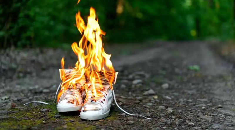 vecteezy_used-white-high-sneakers-burning-on-a-rural-road-that-runs_41506153