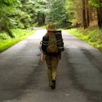 vecteezy_young-woman-hiker-walking-on-narrow-road-through-summer_7665864