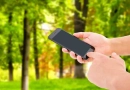 vecteezy_hand-hold-phone-and-touch-screen-on-blurred-park-background_3737348