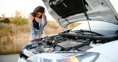 A distressed young woman standing next to her disabled car